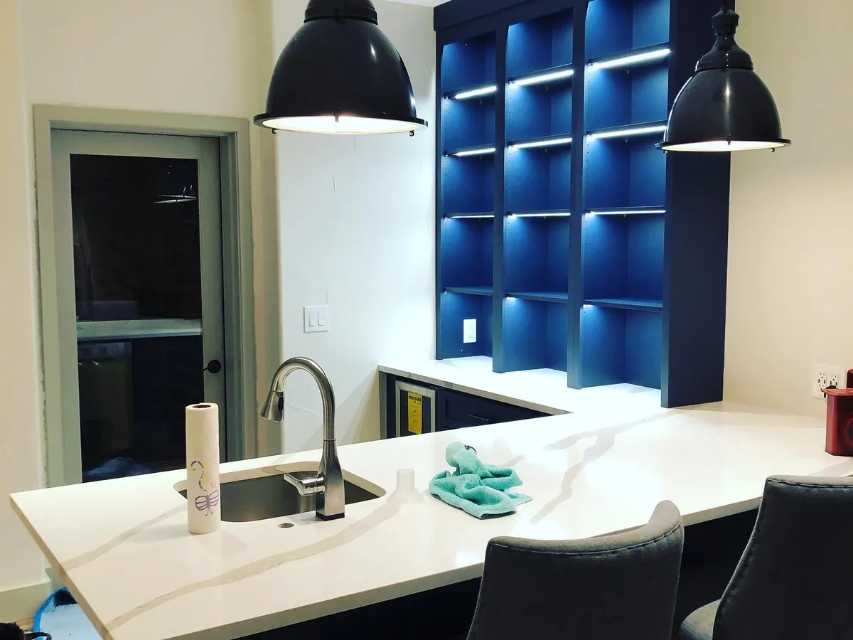 Kitchen bar with two black pendants and blue backlit shelving