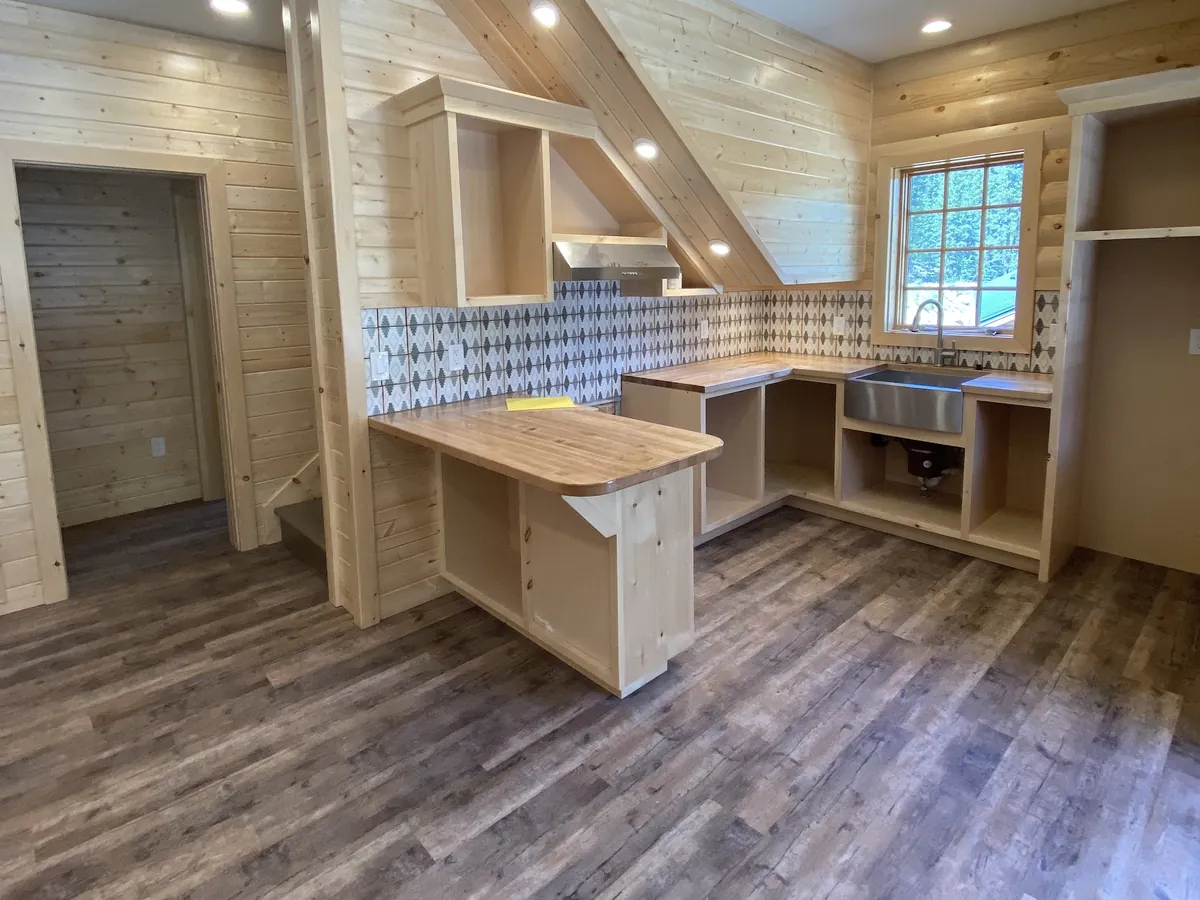 Wood cabin kitchen under construction with open shelving and a flush ceiling light