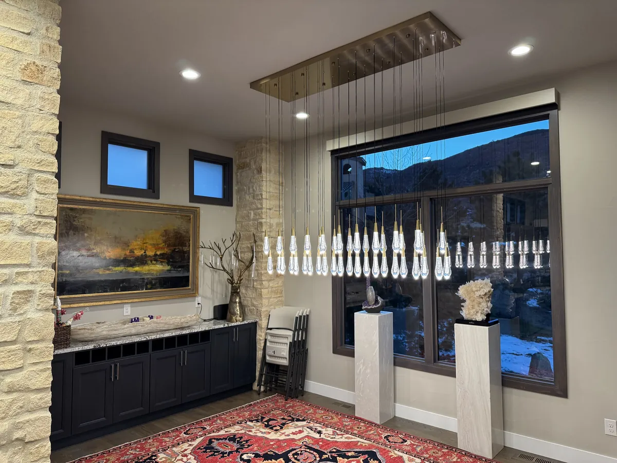 Rectangular crystal pendant with dozens of glass drops in front of a large window at dusk