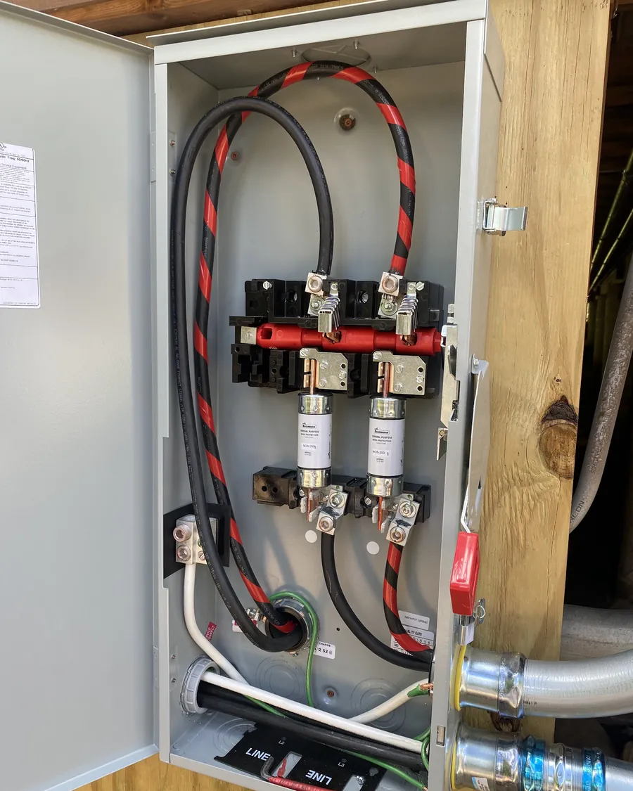 Open fused disconnect switch with red and black conductors and cartridge fuses