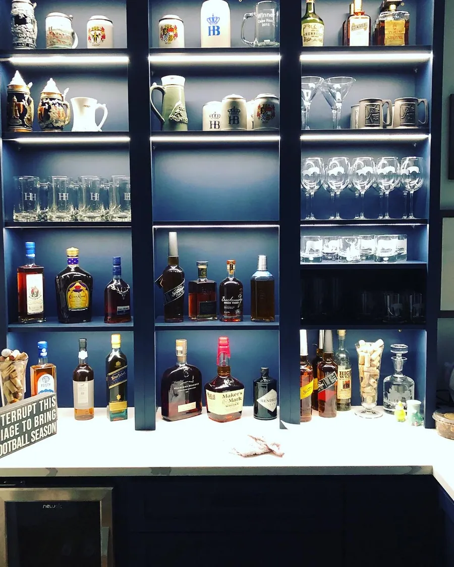Navy bar shelving lit from within, lined with bottles and glassware