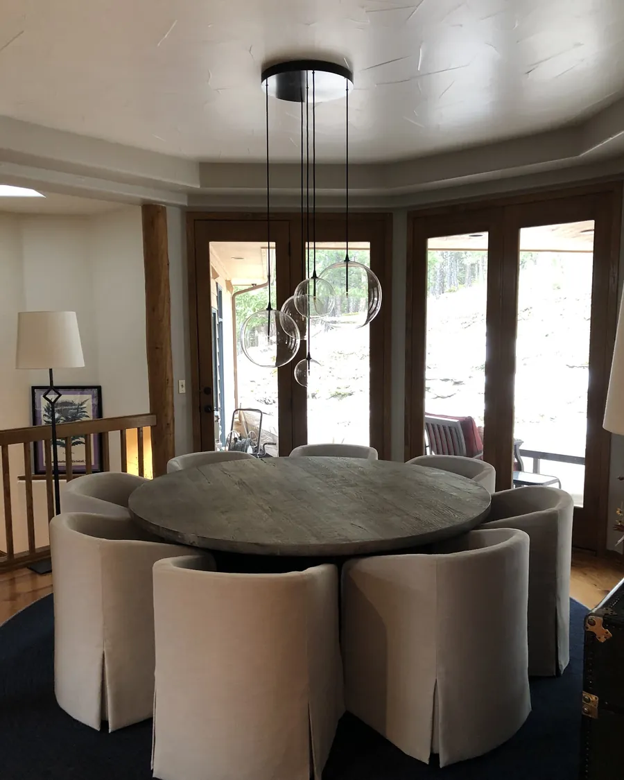 Modern pendant over a round wood dining table with upholstered chairs