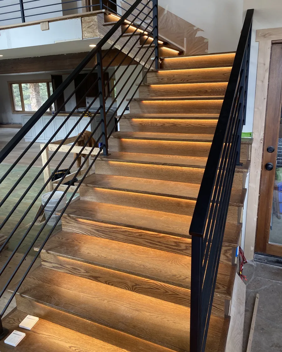 Open staircase with warm LED strip light under each tread and a black steel railing