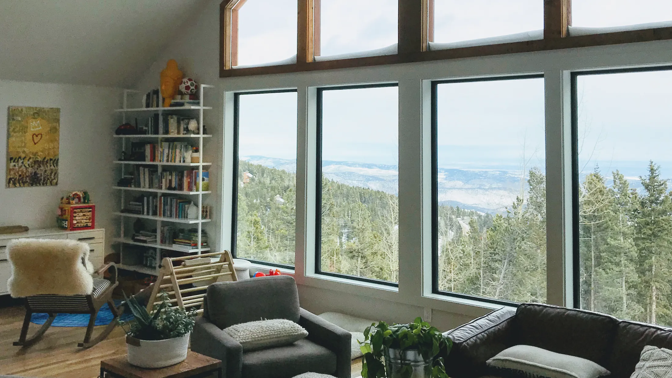 Living room with tall gable windows looking out over forested foothills